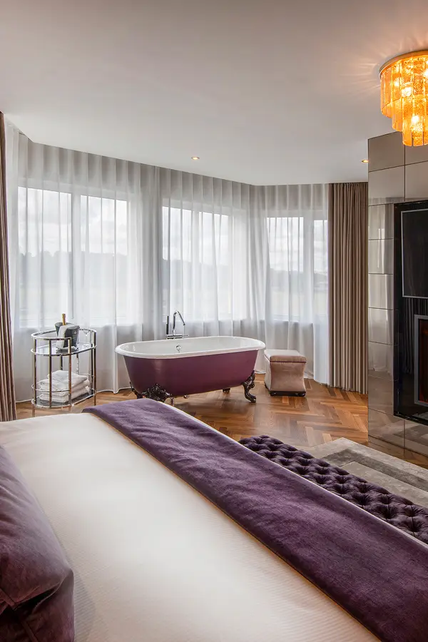 Hotel suite with clawfoot tub and velvet bedding