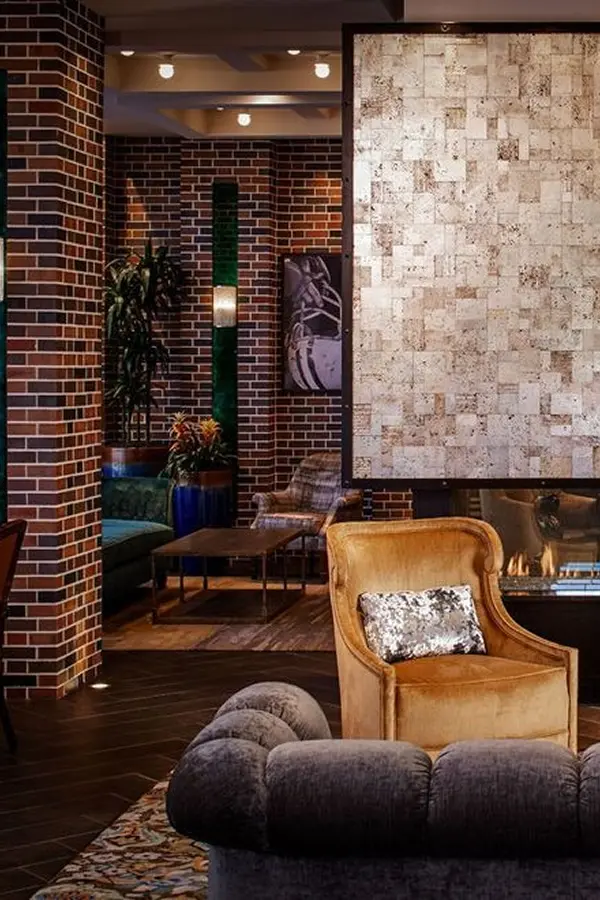 Lounge with brick pillars, stone art panel, and velvet seating